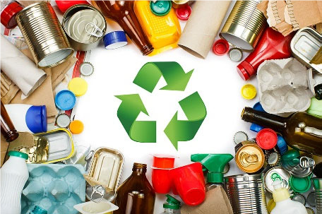 Photo of the recycling symbol, surrounded by materials that can be recycled